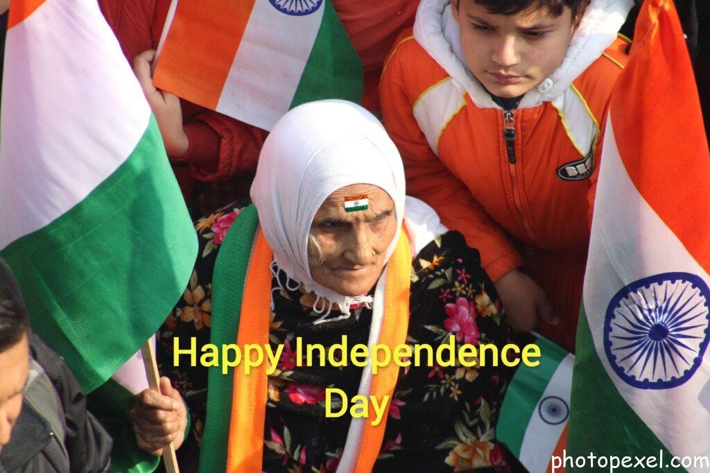 An-Elderly-Woman-Sitting-With-A-Group-Of-People-While-Holding-A-Flag-Happy-Independence-Day